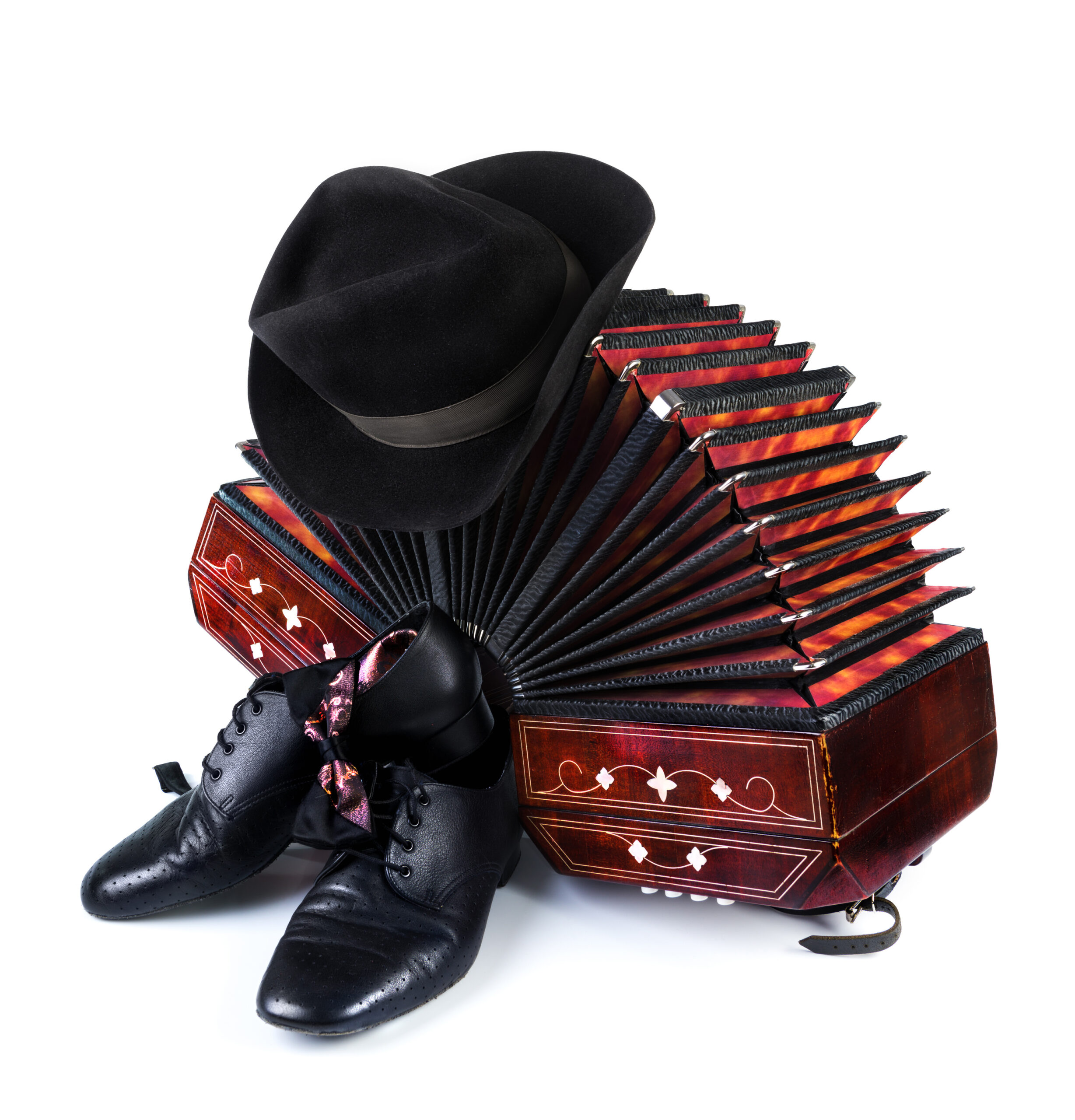 Bandoneon, pair of tango shoes, necktie and a black hat on white background
